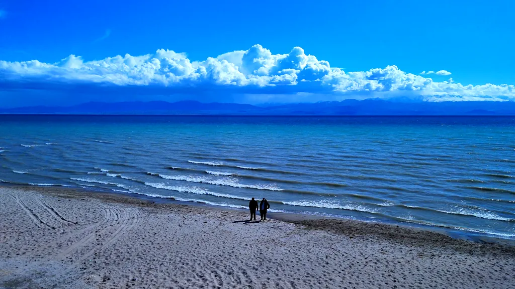 Tourists on the beach near Lake Issyk-Kul in early spring