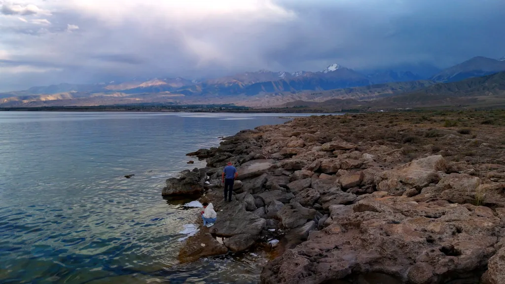 Tourists on the stone shore of Lake Issyk-Kul in the evening