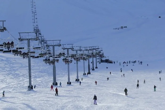 View of lifts and skiers/snowboarders on the slopes of Chunkurchak ski base in Kyrgyzstan